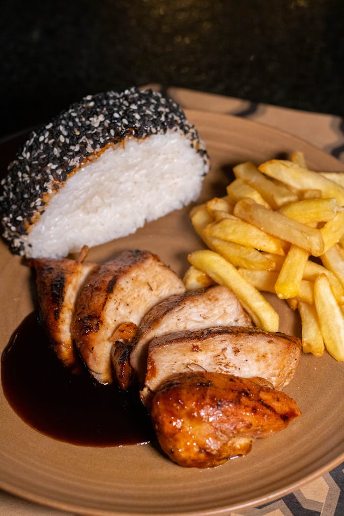Close-up of a savory chicken dish with fries and rice, perfect for dinner inspiration.