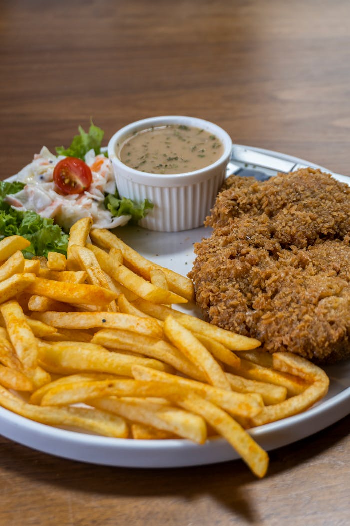 Delicious crispy fried chicken served with fries, salad, and dipping sauce for a satisfying meal.
